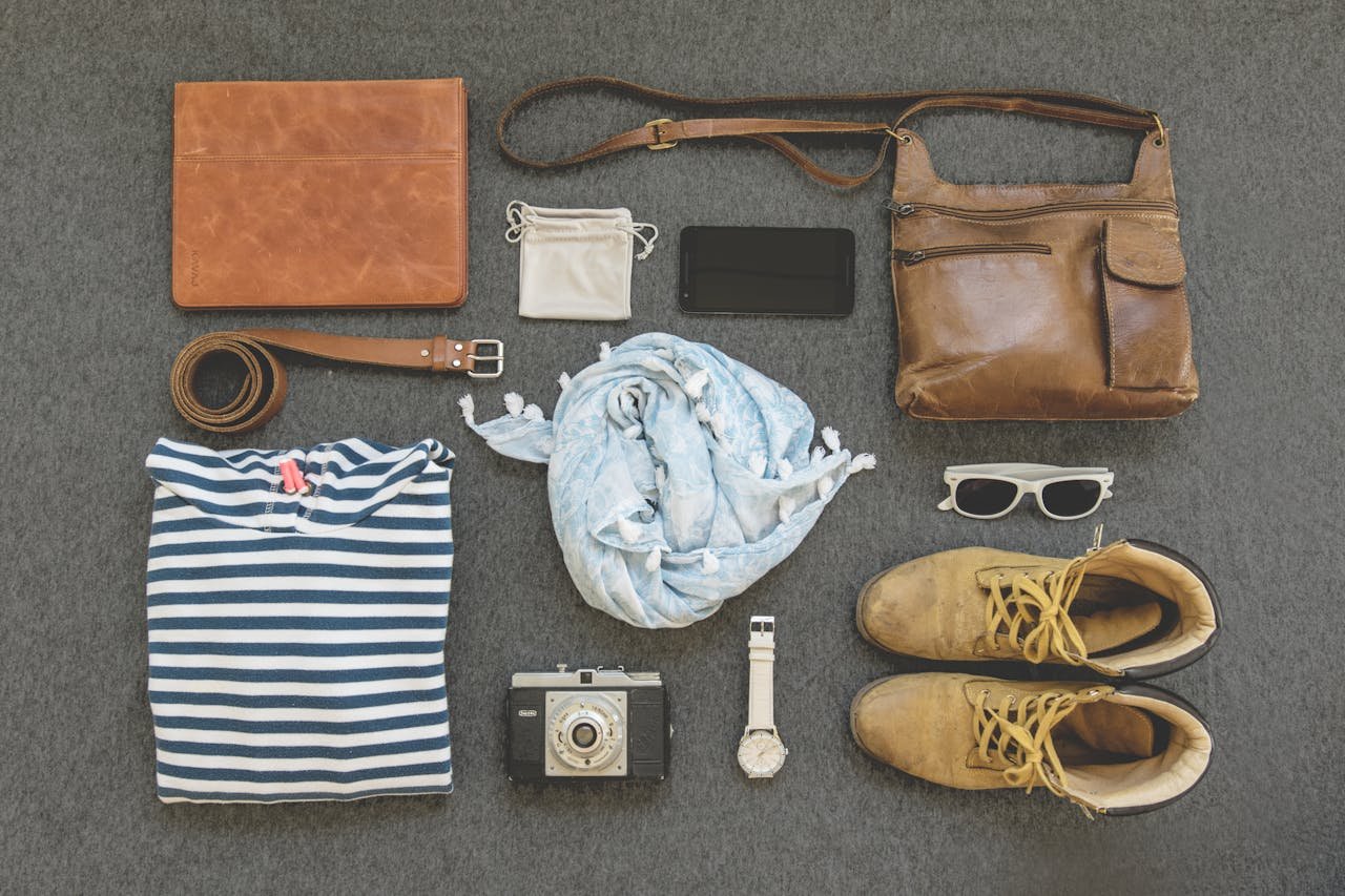 digital Vintage travel essentials flat lay with leather bags, shoes, camera, and clothing.